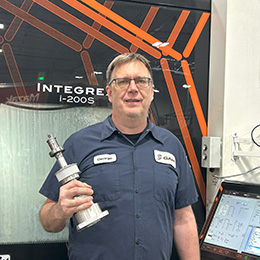 George, holding the GAMMY and standing in front of a CNC machine